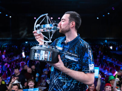 Luke Humphries holding the Winmau World Masters trophy on stage.